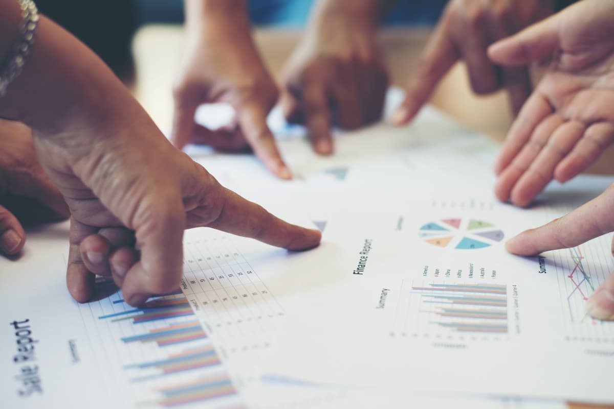 Team collaboration - hands pointing at business documents and charts